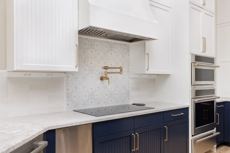 Induction cooktop, pot filler, navy base cabinets and white range hood
